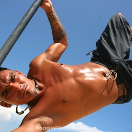 Young man practicing pole acrobatics in the beach during a sunny day. Playa del Carmen, Quintana Roo, México